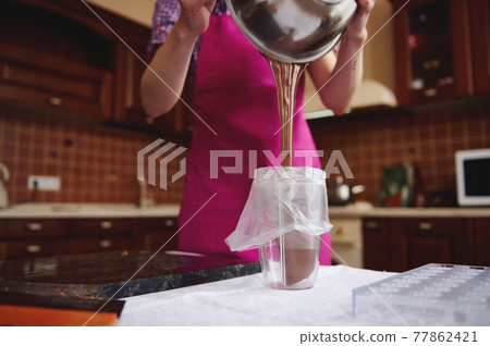 Process of pouring liquid chocolate mass into a confectionery bag before preparing homemade pralines 77862421
