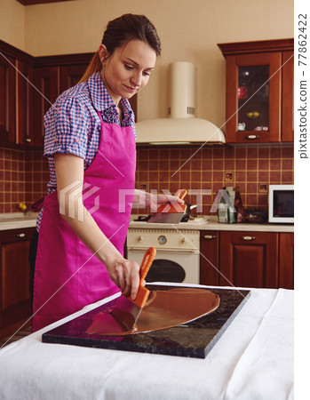 Confectioner cools a sweet chocolate on work marble surface for making handmade desserts 77862422