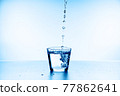 water splashing from glass isolated on blue background 77862641