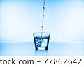 water splashing from glass isolated on blue background 77862642