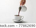 Pouring coffee on a cup isolated on white background 77862690