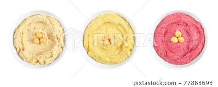 Hummus dips, in white bowls. Middle Eastern dip, a spread made of cooked, mashed chickpeas, blended with tahini, lemon juice and garlic. Three variants made with cumin, curry and beetroot. Food photo. 77863693