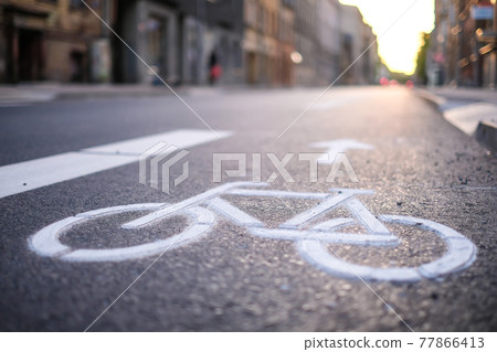 Separate bicycle lane for riding bicycles. A white bicycle symbol on the road. Selective focus 77866413