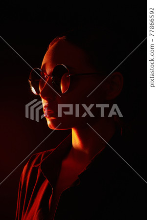woman in sunglasses. Girl in red light 77866592