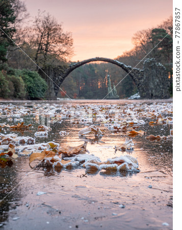 Full moon light on frozen lake with colorful leaves, round Rakotzbruecke Full moon light on frozen lake with colorful leaves, round Rakotzbruecke 77867857