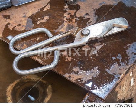 Diamond shear tool on wet steel table in glass blowing art studio Diamond shear tool on wet steel table in glass blowing art studio 77867861