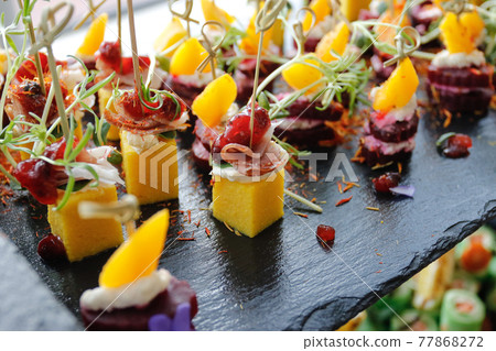 A set of mango, bacon and greens appetizers on a buffet table 77868272