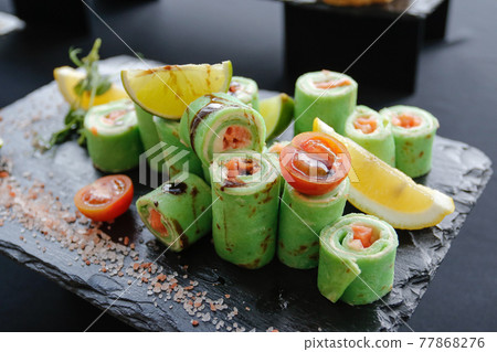 Set of rolls of avocado, cream cheese and red fish with lemon and lime wedges 77868276