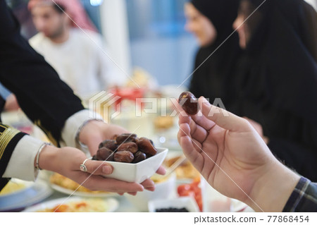 Muslim family starting iftar with dates during Ramadan 77868454