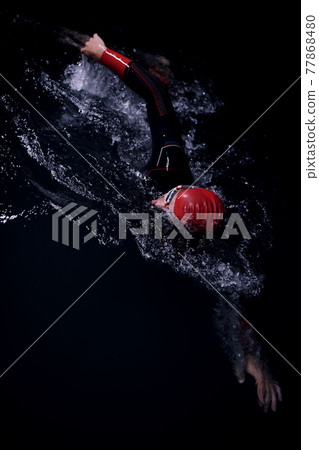 triathlon athlete swimming in dark night wearing wetsuit 77868480