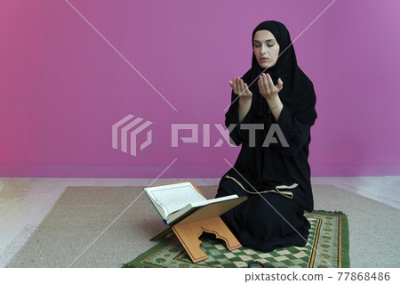 Middle eastern woman praying and reading the holy Quran 77868486