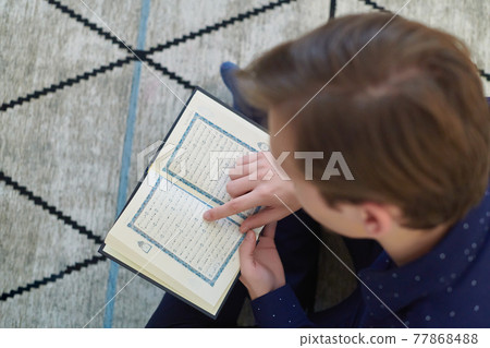 Young muslim man reading Quran during Ramadan 77868488