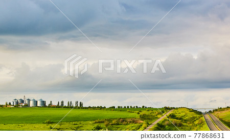 Farm silos at a distant farm at sunset. Farm silos at a distant farm at sunset. 77868631