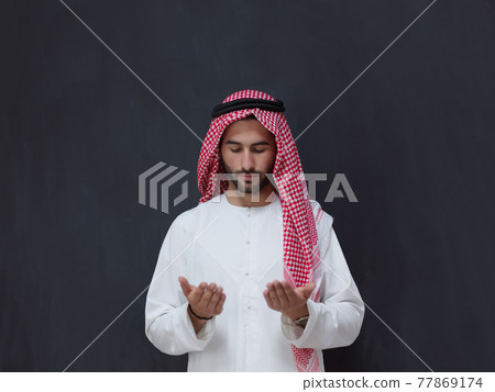 Arab man in traditional clothes praying to God or making dua Arab man in traditional clothes praying to God or making dua 77869174