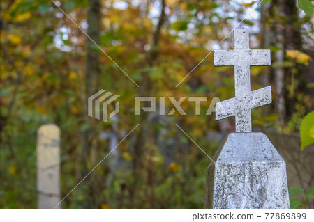 Grave monument in the form of an orthodox silver cross. Autumn graveyard background Grave monument in the form of an orthodox silver cross. Autumn graveyard background 77869899