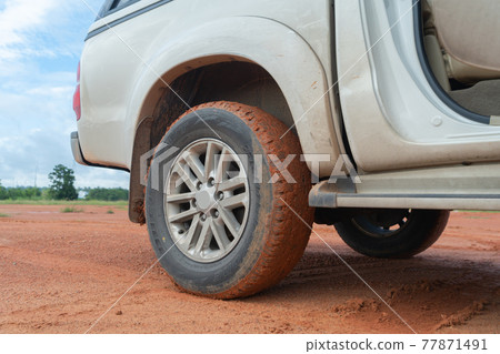 Muddy car tire wheel, red soil surface dirt road. Adventure in journey. Mud. Muddy car tire wheel, red soil surface dirt road. Adventure in journey. Mud. 77871491