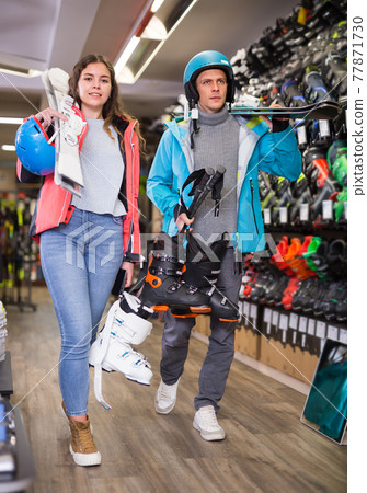 man and woman in helmets choosing sports equipment man and woman in helmets choosing sports equipment 77871730