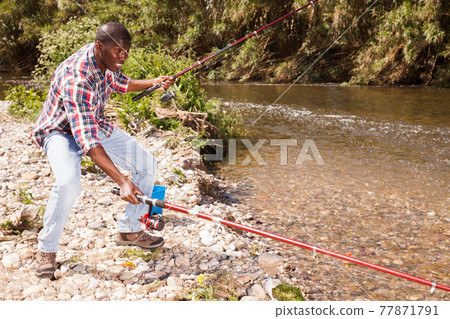 Man pulling fish with two rods Man pulling fish with two rods 77871791
