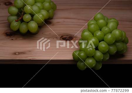 A photo of two muscats on a black background, a variety called Shine Muscat A photo of two muscats on a black background, a variety called Shine Muscat 77872299