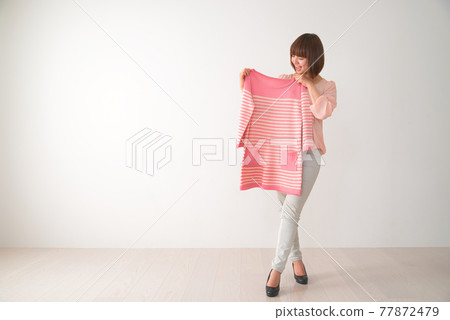 一個年輕女子試圖在她的身體前搭配粉紅色條紋衣服 一個年輕女子試圖在她的身體前搭配粉紅色條紋衣服 77872479