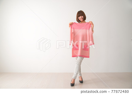 一個年輕女子試圖在她的身體前搭配粉紅色條紋衣服 一個年輕女子試圖在她的身體前搭配粉紅色條紋衣服 77872480
