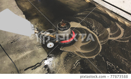 Oil-stained floor. A professional man cleans the garbage room floor, with a professional scrubber. 77873588