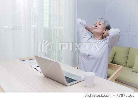 Elderly professional woman working from home during covid-19 pandemic 77875163