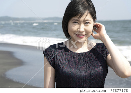 吹著海風在海邊散步的年輕女子（神奈川縣鎌倉市七里濱） 77877178