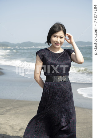 吹著海風在海邊散步的年輕女子（神奈川縣鎌倉市七里濱） 77877194