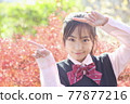 Student uniforms guided by autumn leaves back 77877216