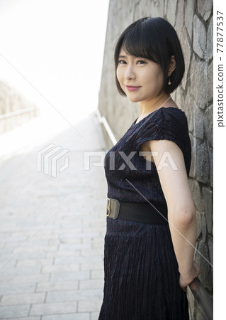A young woman leaning on the railing of an underpass slope A young woman leaning on the railing of an underpass slope 77877537