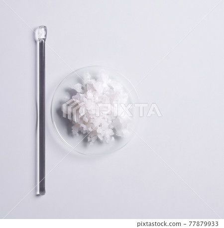 Spa product (Sea Salt) in chemical watch glass placed next to the stirring rod. Cosmetic chemical on white laboratory table. 77879933