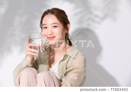 一個年輕女子拿著一杯水來補充水分 77883403