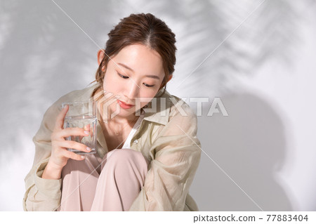 A young woman holding a glass of water for hydration 77883404