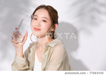 Young woman holding a plastic bottle of water for hydration 77883430