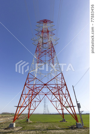Power transmission tower standing on farmland 77883456