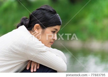 一個女人低頭看著新鮮綠色河岸上的河流 77883795