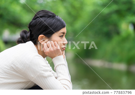 一個女人低頭看著新鮮綠色河岸上的河流 77883796