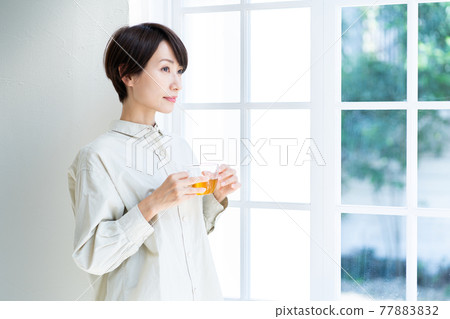 Woman drinking tea by the window Woman drinking tea by the window 77883832