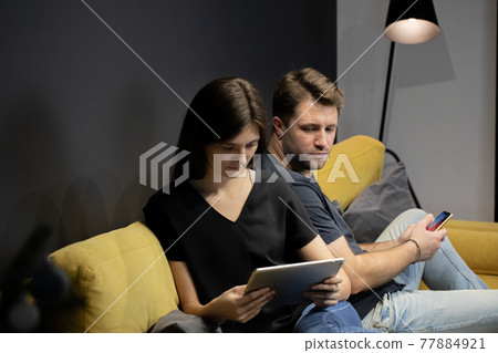 guy jealously peeks into girlfriend's tablet to see who she is chatting with guy jealously peeks into girlfriend's tablet to see who she is chatting with 77884921