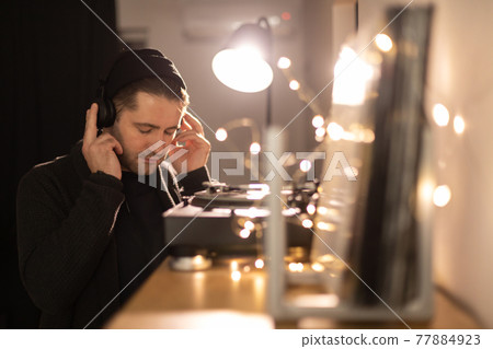 Young unshaven handsome hipster eyes closed guy listens to music with headphones Young unshaven handsome hipster eyes closed guy listens to music with headphones 77884923