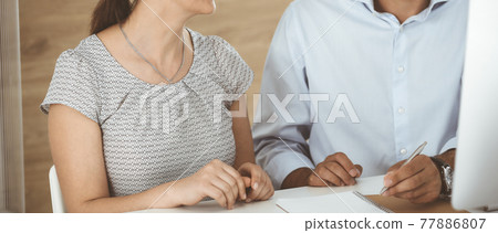 Unknown businessman and woman working with computer in a modern office, close-up. Group of diverse people. Teamwork, partnership and business concept 77886807