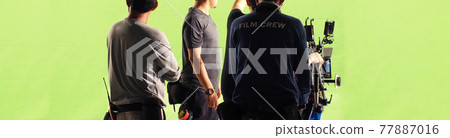 Film Production. Back of videoographer and film crew team with 4k high definetion online video camera and green screen background for make movie shooting in big studio. Video production. 77887016