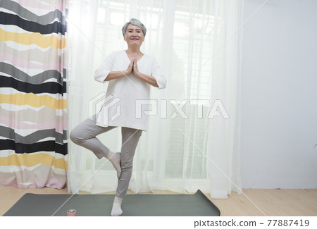 Seniors doing yoga and aerobics at home 77887419