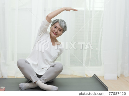 Seniors doing yoga and aerobics at home 77887420