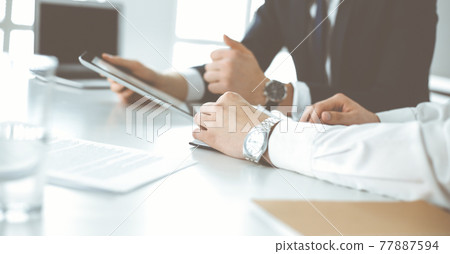 Unknown business people using tablet computer in modern office. Businessman or male entrepreneur is working with his colleague at the desk 77887594