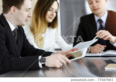 Business people or lawyers discussing questions at meeting in sunny office. Unknown businessman and woman with colleague sitting and working at the glass desk Business people or lawyers discussing questions at meeting in sunny office. Unknown businessman and woman with colleague sitting and working at the glass desk 77887661