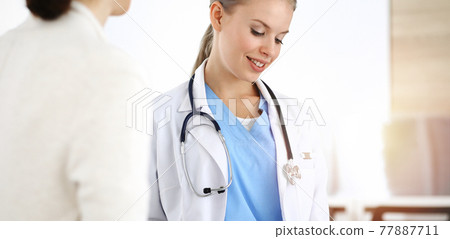 Woman - doctor consults her female patient in sunny clinic Woman - doctor consults her female patient in sunny clinic 77887711