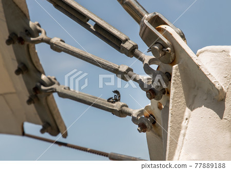 Connection points of tension membrane roof. Turnbuckle wire rope tension for tension membrane roof on a blue sky background. Connection points of tension membrane roof. Turnbuckle wire rope tension for tension membrane roof on a blue sky background. 77889188