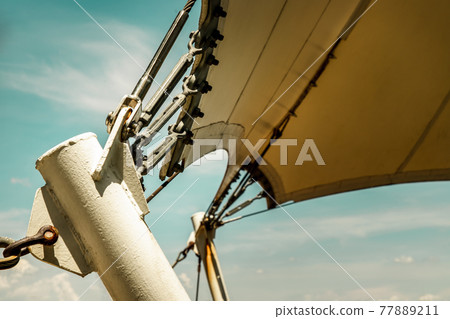 Connection points of tension membrane roof. Turnbuckle wire rope tension for tension membrane roof on a blue sky background. Connection points of tension membrane roof. Turnbuckle wire rope tension for tension membrane roof on a blue sky background. 77889211
